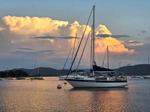 a sail boat sitting in the water with a sunset at Woodpecker cottage in Hartbeespoort +6 photos