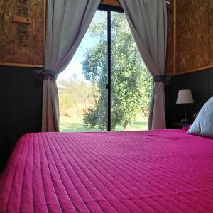 a bedroom with a pink bed with a window at cabañas roccajoma in Salto del Laja