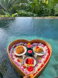 a tray of food in the shape of a heart next to a pool at The Oding House in Ubud