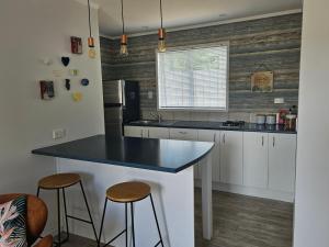 a kitchen with white cabinets and a black counter top at Diamond Retreat in Tairua