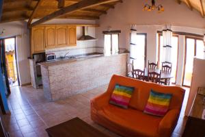 a living room with an orange couch and a kitchen at Casarural Vallecillo in Vallecillo