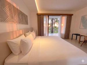 a bedroom with a large white bed with pillows at Palm Springs Bali Dive Resort in Tulamben