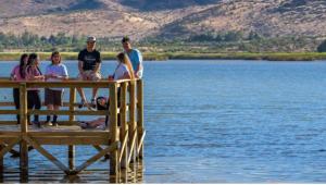 a group of people sitting on a dock in the water at la casa del cerro in Casas de Batuco