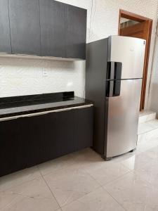 a kitchen with a stainless steel refrigerator and black cabinets at Estrela-do-mar in Serra