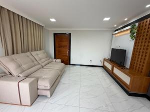a living room with a couch and a flat screen tv at Estrela-do-mar in Serra