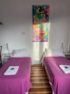 two beds in a room with a painting on the wall at Balcones de Cabrera in Buenos Aires +10 photos