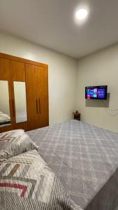 a bedroom with a bed and a tv on the wall at Flat Ubuntu in Viçosa do Ceará