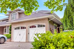 a house with two white garage doors at Surrey Two Bedroom Suite with Pool Access in Surrey