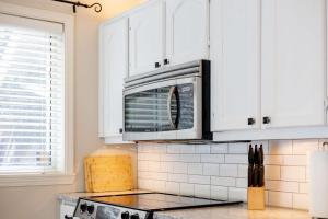 a kitchen with white cabinets and a microwave at Surrey Two Bedroom Suite with Pool Access in Surrey +40 photos