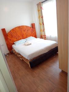 a bedroom with a bed with a wooden headboard and a window at Kitengela prime suites in Kitengela 