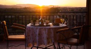 a table with wine glasses on a balcony with the sunset at Dar Amoudou in Ouarzazate