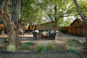 a patio with chairs and a table under a tree at Primrose Inn and Suites in Chino Valley