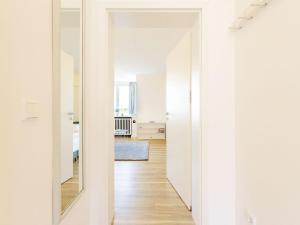 a hallway with white walls and a mirror at Kliffsand-68 in Kampen +1 photo