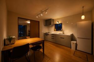 a kitchen with a wooden table and a refrigerator at SaiKa 隠れ家 in Saikamachi