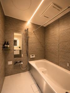 a bathroom with a white tub and a shower at SaiKa 隠れ家 in Saikamachi