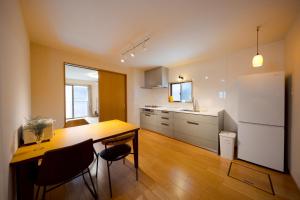 a kitchen with a table and chairs and a refrigerator at SaiKa 隠れ家 in Saikamachi