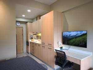 a kitchen with a desk and a tv on a wall at Stylish Studio Condo on the Beach in Ban Pak Khlong Phe