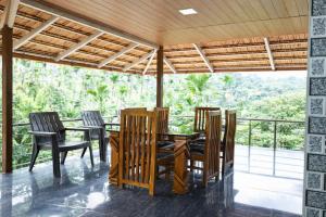 a dining room with a table and chairs on a balcony at Peak Homestay in Kalasa