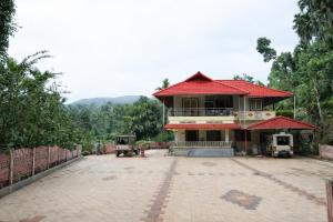 a building with a red roof in a courtyard at Peak Homestay in Kalasa