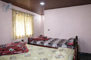 two beds in a room with a window at Peak Homestay in Kalasa +3 photos