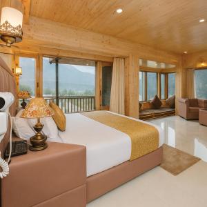 a bedroom with a large bed and a balcony at Himalayan Fort Resort, Manali - A Riverside Retreat in Manāli