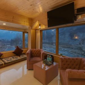 a living room with couches and a large window at Himalayan Fort Resort, Manali - A Riverside Retreat in Manāli +52 photos