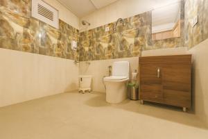 a bathroom with a toilet and a wooden cabinet at Himalayan Fort Resort, Manali - A Riverside Retreat in Manāli