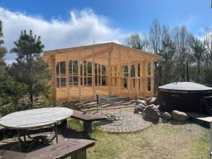 a wooden cabin with a picnic table and a hot tub at Feniksiukas in Agluonėnai