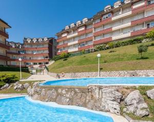 a swimming pool in front of a large building at Apartamentos Acacio in Suances