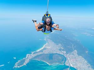 a man hanging from a rope in the air over the ocean at Coastal Hideaway at Pelican in Pelican Flat