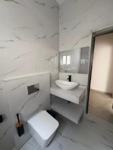 a white bathroom with a toilet and a sink at Appartement 2 chambres in Cotonou +26 photos
