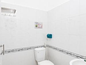 a white bathroom with a toilet and a sink at The Red Hotel Côn Đảo in Con Dao