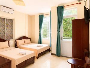 a bedroom with two beds and a window at The Red Hotel Côn Đảo in Con Dao