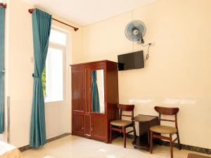 a room with two chairs and a table and a tv at The Red Hotel Côn Đảo in Con Dao