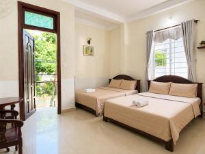two beds sitting in a room with a window at The Red Hotel Côn Đảo in Con Dao +17 photos