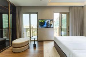 a bedroom with a bed and a stool and windows at Villa 5 phòng ngủ cao cấp in Dong Hoi