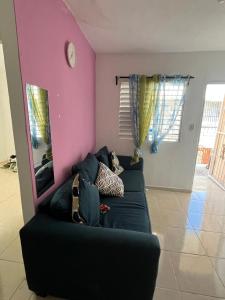 a living room with a black couch and a pink wall at María 1 in Barahona