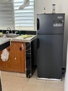 a kitchen with a black refrigerator and a sink at María 1 in Barahona