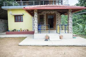 a small yellow house with a gate in front of it at Aroli Homestay in Kalasa