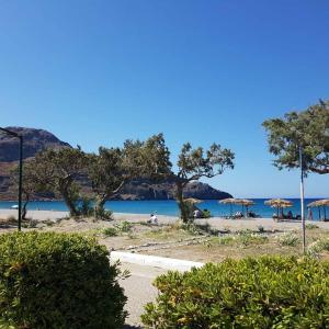 a beach with umbrellas and people on the beach at Villa Joanna Seasides , Top Floor in Mesimérion