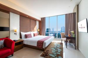 a hotel room with a bed and a red chair at The Margo Hotel in Depok +31 photos