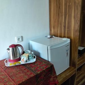 a kitchen with a refrigerator and a tea kettle on a table at Gecko Lodge in Tetebatu