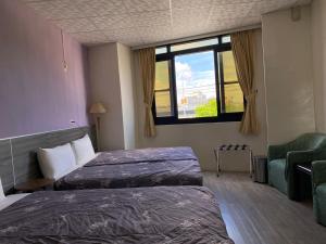 a hotel room with two beds and a window at 東石民宿 湛藍海寓 Azure Seaside House in Dongshi