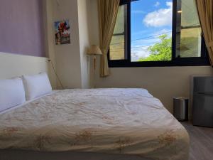 a bedroom with a bed and a window at 東石民宿 湛藍海寓 Azure Seaside House in Dongshi