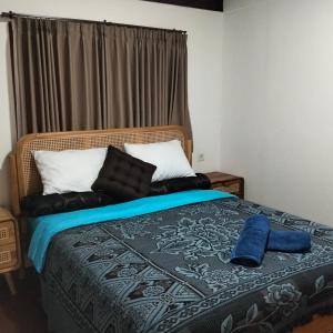 a bedroom with a bed with a blue blanket and pillows at Gecko Lodge in Tetebatu