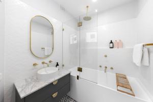 a white bathroom with a sink and a mirror at 3 Bedroom City Apt, Big Yard & Park Views - Sleeps 7 in Adelaide