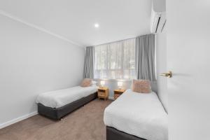 a room with two beds and a window at 3 Bedroom City Apt, Big Yard & Park Views - Sleeps 7 in Adelaide