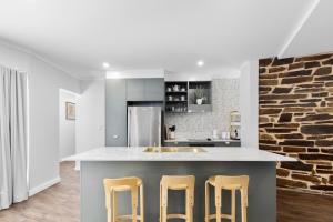 a kitchen with a counter with three stools at 3 Bedroom City Apt, Big Yard & Park Views - Sleeps 7 in Adelaide