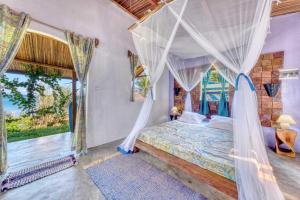 a bedroom with a canopy bed and a large window at Villa Lokobe in Hell-Ville