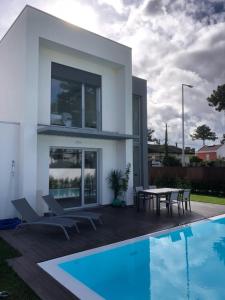a white house with a table and a swimming pool at Aroeira Villa B&B in Charneca